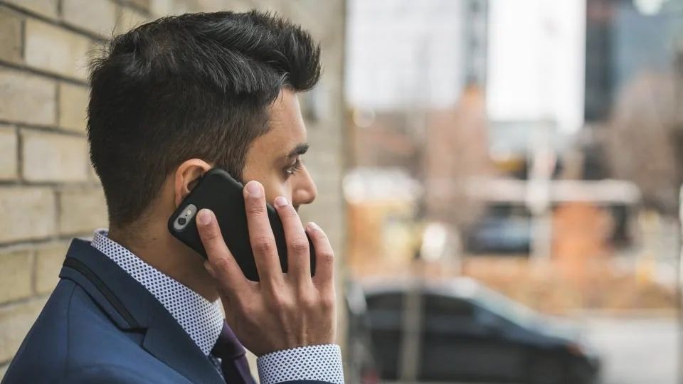 Takım elbiseli bir adam sokakta telefonla konuşuyor