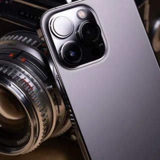 Eski bir fotoğraf makinesi merceği ve yanında bir akıllı telefon